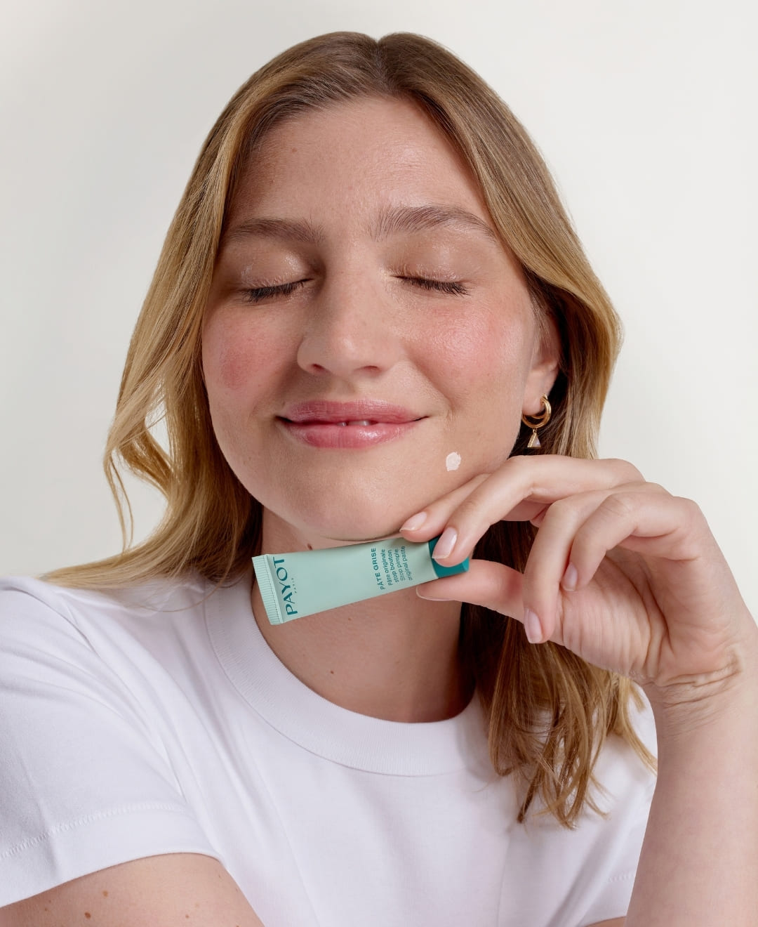 Femme utilisant la Pâte Originale Stop Bouton Pâte Grise PAYOT sur une imperfection du menton, disponible sur la boutique en ligne de Concept Beauté.