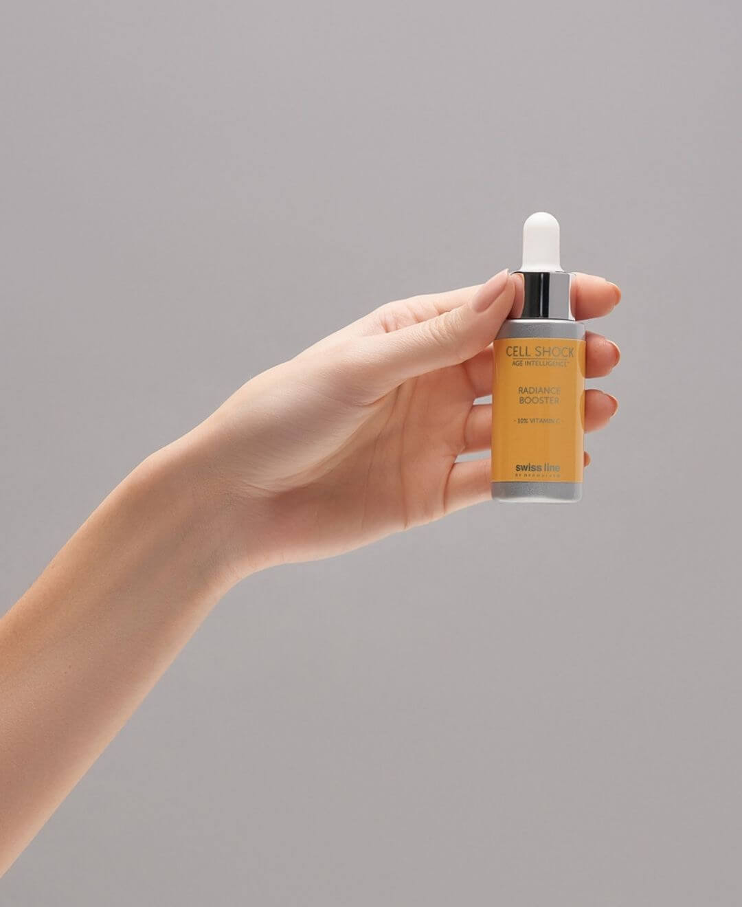 Sérum Radiance Booster Cell Shock de Swissline tenu à la main, soin éclat à la vitamine C pour illuminer le teint.
