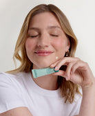 Femme utilisant la Pâte Originale Stop Bouton Pâte Grise PAYOT sur une imperfection du menton, disponible sur la boutique en ligne de Concept Beauté.