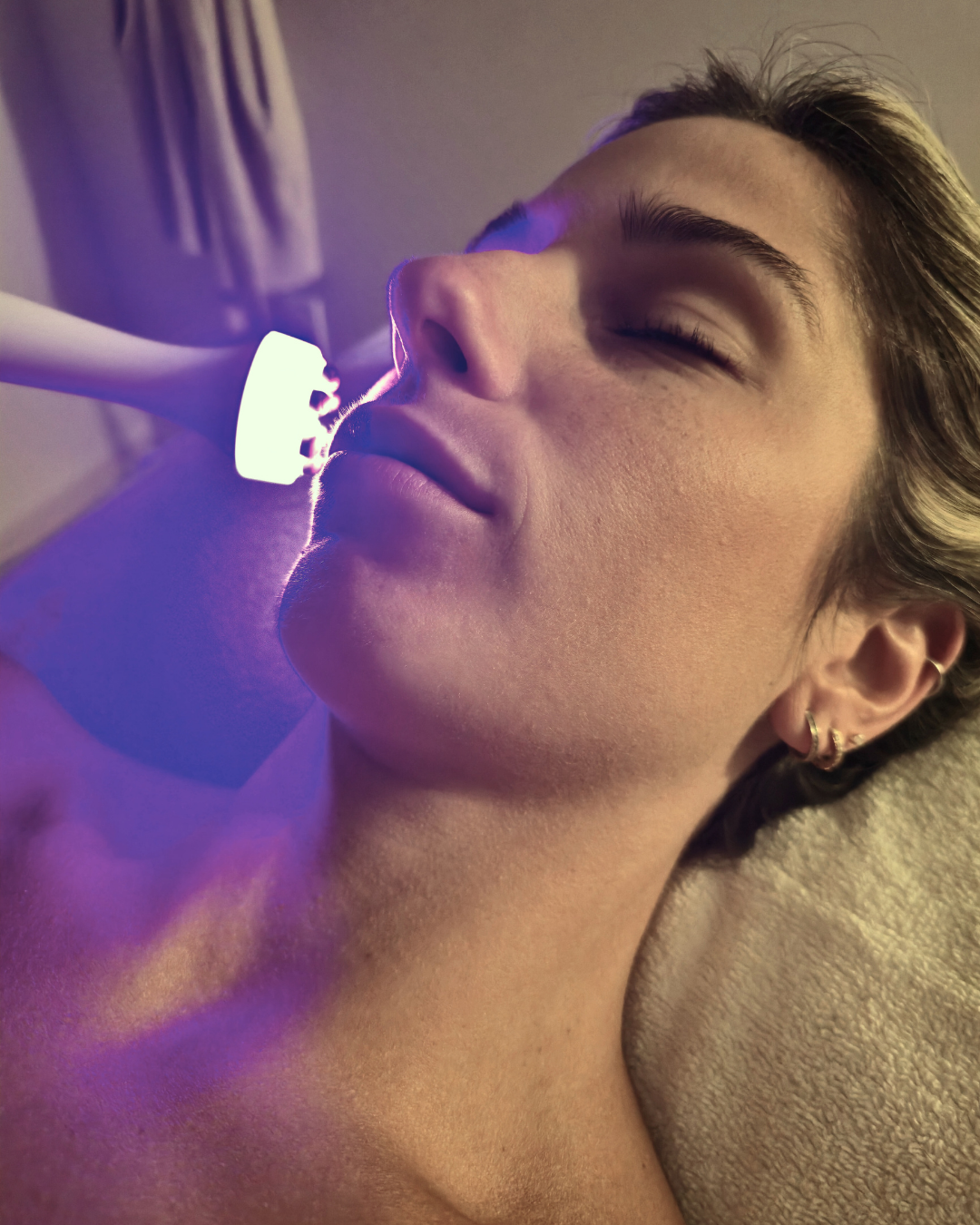 Femme recevant un soin du visage BELA MD en clinique médico-esthétique, appareil à lumière bleue appliqué sur la peau pour un traitement complet. Ce soin de nouvelle génération exfolie en profondeur, nettoie les impuretés, nourrit la peau avec des sérums ciblés et stimule l’oxygénation cellulaire. Résultat : un teint lumineux, une peau plus lisse et revitalisée dès la première séance. Disponible dans nos cliniques Concept Beauté à Cap-Rouge, Charlesbourg et Lac-Beauport ou sur la boutique en ligne de Concep